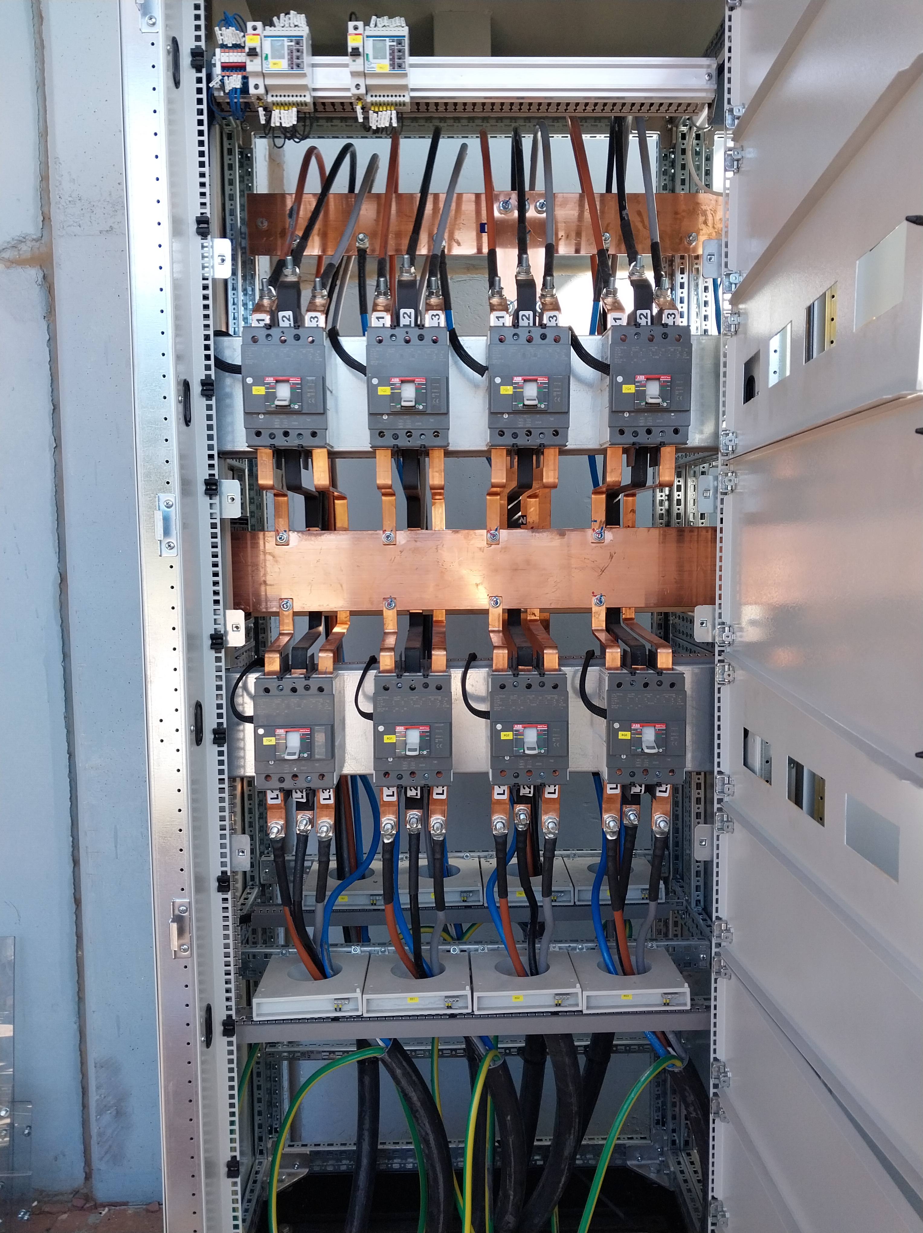 Temiz ve profesyonelce düzenlenmiş güç panosu içinde bakır baralar, otomatik şalterler ve kalın kabloları gösteren dikey elektrik panosu detayı.